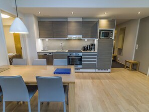 Una cocina moderna con comedor, que incluye una mesa con sillas, un microondas y una cafetera.
