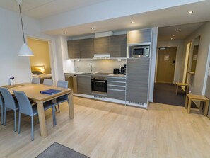 A modern kitchen with a dining area, featuring a table with chairs, a microwave, and a coffee maker. - Ruka ski chalets ii huoneisto 2605 by Interhome (Kuusamo)