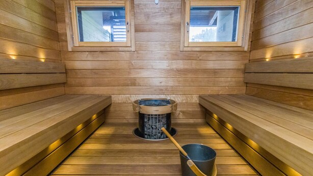Un sauna avec des bancs en bois, deux fenêtres et un système de chauffage central.