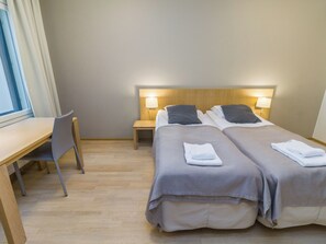 Habitació d'hotel amb dos llits, una taula i una cadira.