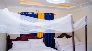 A four-poster bed with white linens, a canopy, and a blue and yellow curtain backdrop. - Homely, Lovely and spacious 3-bedroom bed & breakfast in Bungoma (Bungoma)