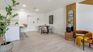 A modern living room with a dining area, a large mirror, and a potted plant.