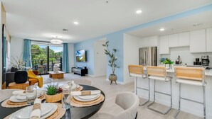 A modern living room with a dining area, a kitchen, and a balcony with a view.