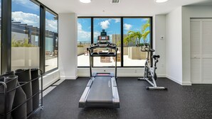 A gym with a treadmill, stationary bike, and exercise mats.