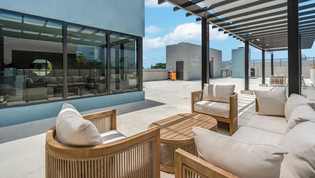 A rooftop patio with outdoor seating, large windows, and a covered area.
