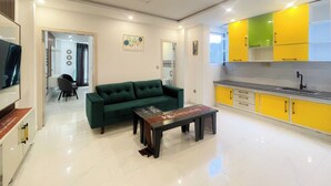 Ein modernes Wohnzimmer mit einem grünen Sofa, einem Couchtisch und einem Essbereich mit gelben Schränken.