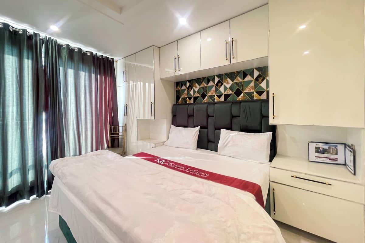 A hotel room with a large bed, white cabinets, and a decorative headboard.