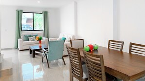 Una sala de estar moderna con comedor, que incluye un conjunto de sofá, una mesa de centro y una mesa de comedor con sillas.