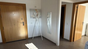 A room with wooden doors, a white wall with a mirror, and a white rug on the floor. - Welooveyou Wildlife Zen (La Lajita)
