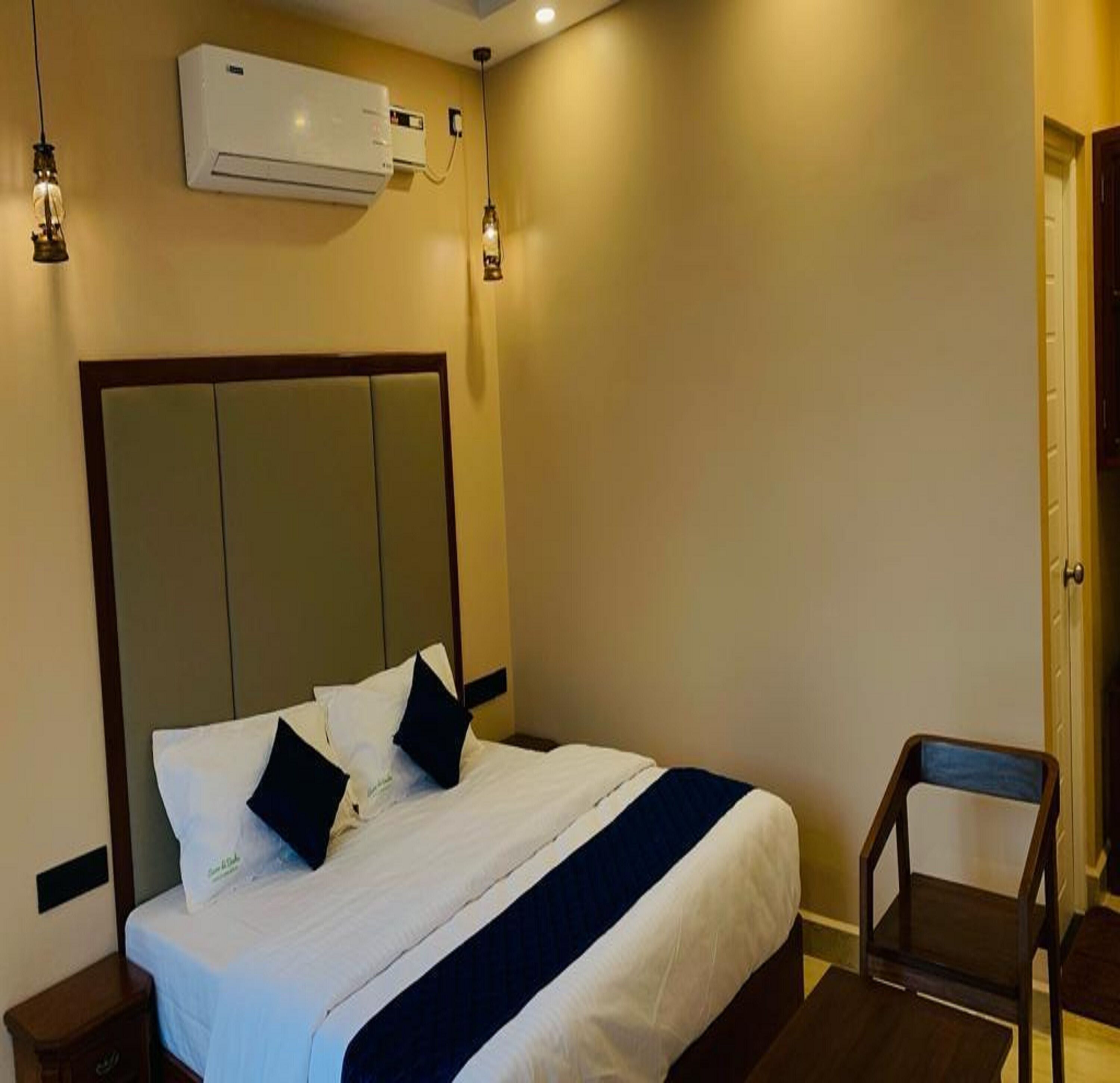 Una camera d'albergo con un letto, una sedia, un condizionatore d'aria e una porta.