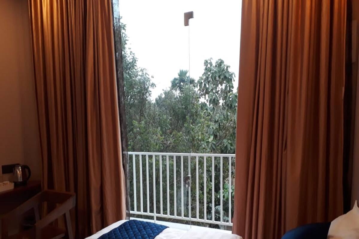 A hotel room with a bed, a desk, and a balcony with a white railing.