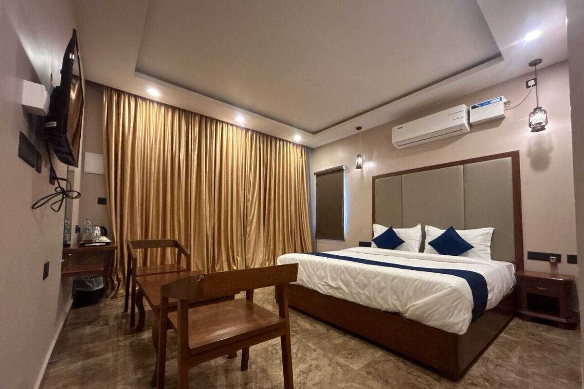 A hotel room with a bed, a desk, a chair, and a TV.
