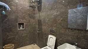 Un baño con inodoro, bidé y lavamanos, todo con paredes de mármol y suelo de baldosas.