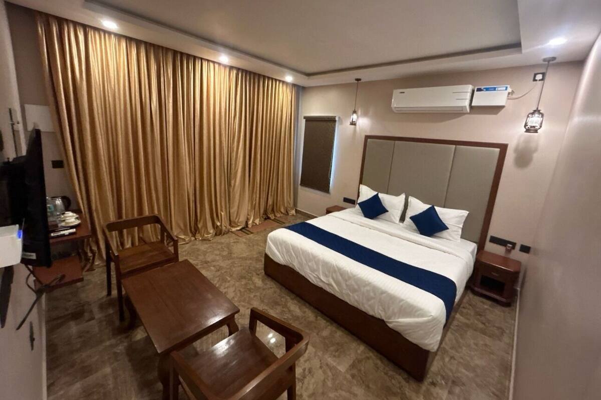 A hotel room with a large bed, a desk, a chair, and a television.