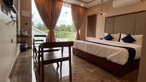Habitación de hotel con cama, mesa de comedor y sillas. Tiene ventana con cortinas, un equipo de aire acondicionado y un pequeño balcón.