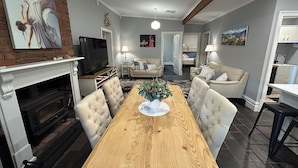A spacious living room with a fireplace, a dining table, and comfortable seating. - "GraciaDeDios" Beautifully renovated 1910 Cottage (Mount Barker)