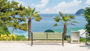 A bench with a view of the sea and a distant island. - Namhae Orda Pool Villa (Namhae)