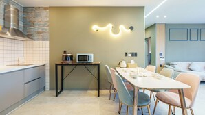 A modern kitchen with a dining area, a microwave, and a kettle on a table. - Namhae Orda Pool Villa (Namhae)