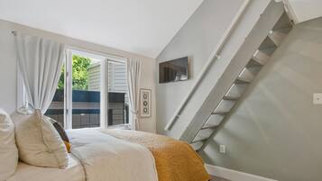 Une chambre à coucher avec un lit, un téléviseur fixé au mur et un escalier.