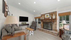 Una sala de estar con chimenea, un sofá, un televisor y una mesa con lámpara.