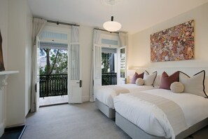 A bedroom with two beds, a balcony, and a large abstract painting.
