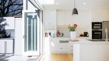 A modern kitchen with white cabinetry, a large island, a hanging pendant light, and a view of the outdoors.
