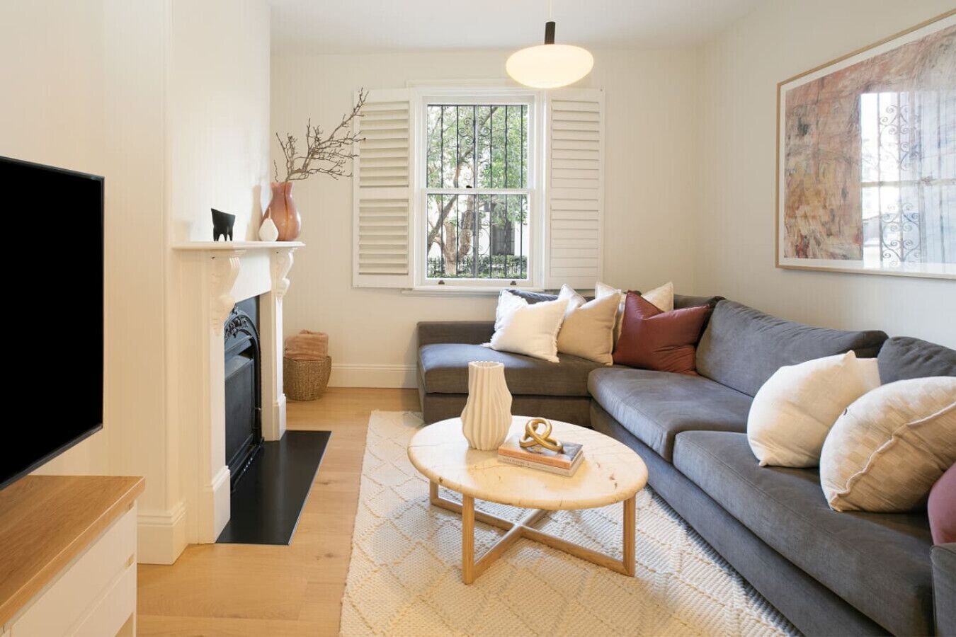 A living room with a sofa, a coffee table, a fireplace, and a television.