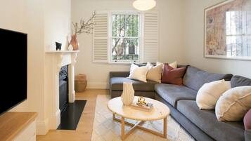 A living room with a sofa, a coffee table, a fireplace, and a television.