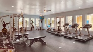 A gym with treadmills, weight machines, and dumbbells.