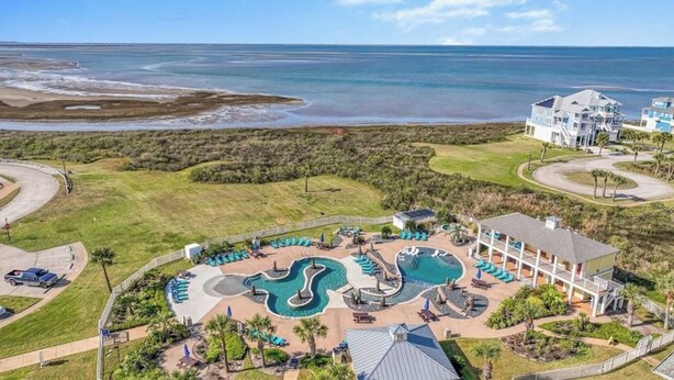 Een resort met een groot zwembadgedeelte, uitzicht op het strand en een gebouw met meerdere balkons.