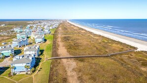 Luchtbeeld van een kustgebied met woonhuizen direct aan het strand, een promenade en een helder uitzicht op de oceaan.