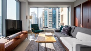 A modern living room with a large TV, a sofa, a green armchair, and a coffee table. - Blueground | Burj Residence Phase I & II, pool, nr Burj Khalifa (Dubai)