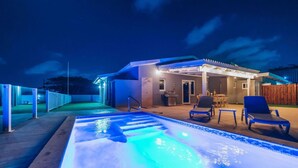 Une piscine avec un jacuzzi, des chaises longues et un patio couvert.