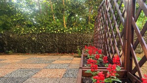 Ein Gartenbereich mit Kiesweg und erhöhten Blumenbeeten, die rote Blüten tragen.