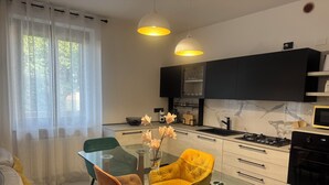 Eine moderne Küche mit einem Glastisch, zwei Stühlen und einer Vase mit Blumen.