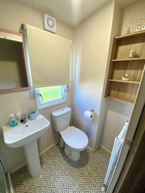 A compact bathroom with a pedestal sink, toilet, and a small window. - The Bolt Hole Polperro (Polperro)