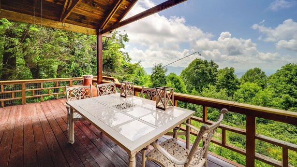 A wooden deck with a table and chairs, overlooking a forested landscape. - Little Switzerland Cabin w/ Stunning Mtn Views (Marion)