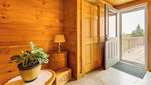 A wooden cabin interior with a potted plant, a lamp, and a door leading to a deck. - The Hideaway in Downeast Maine: Walk to Ocean (Jonesport)