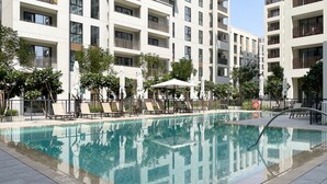 Un hotel moderno con piscina, sillones de descanso y sombrillas.