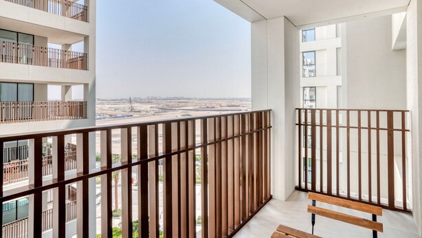 Un balcón con vista a una obra en construcción, una banca de madera y una barandilla.