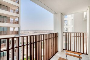 Un balcón con vista a una obra en construcción, una banca de madera y una barandilla.