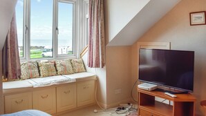 A bedroom with a large window, a television, and a bed with patterned bedding.