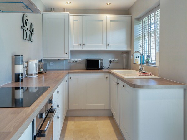 A modern kitchen with white cabinets, a microwave, a kettle, and a sink. - 2 bedroom accommodation in Snettisham (Snettisham)