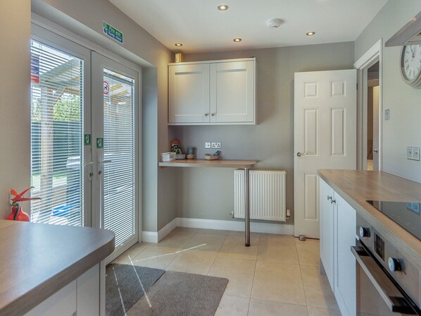 A modern kitchen with white cabinets, a built-in oven, and a countertop. - 2 bedroom accommodation in Snettisham (Snettisham)