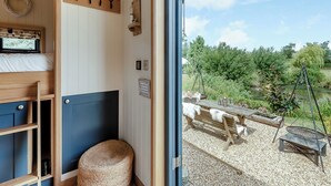 A cozy room with a bed, a small table, and a view of a garden and pond.