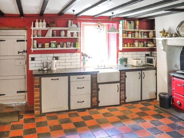 A kitchen with a checkered floor, white cabinets, and various kitchen appliances.