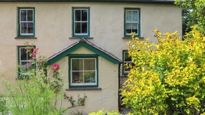 A two-story building with a gabled roof and green window frames.