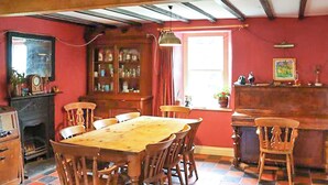 A dining room with a wooden table and chairs, a fireplace, a cabinet with glass doors, and a window with curtains.