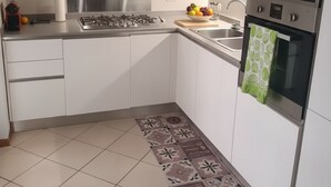 A modern kitchen with white cabinets, a stainless steel stove, a sink, and a built-in oven. - A 10-minute walk from Lake Garda, quiet area, a playground 80 m (Raffa)