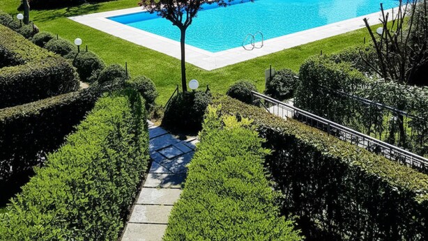 A pool surrounded by well-manicured hedges and a building with a tiled roof. - A 10-minute walk from Lake Garda, quiet area, a playground 80 m (Raffa)